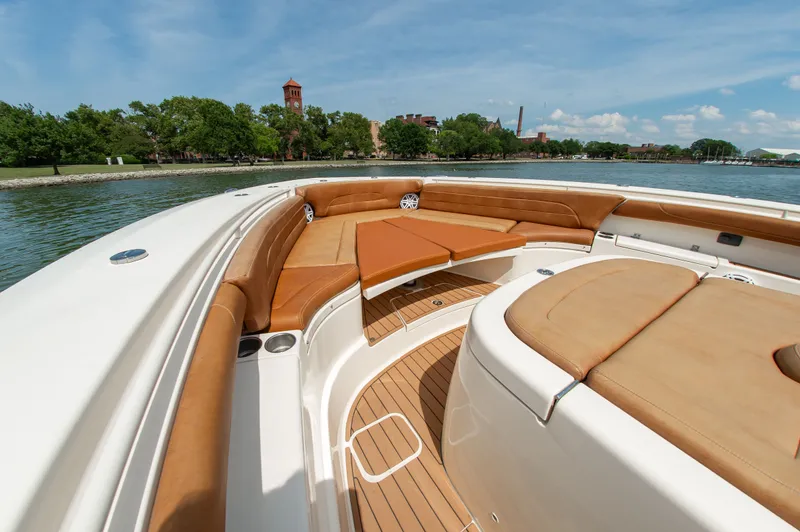 Slide: The Image of 2016 Scout 42LXF with sleek seating and teak flooring, on calm water near a green shoreline. - 17