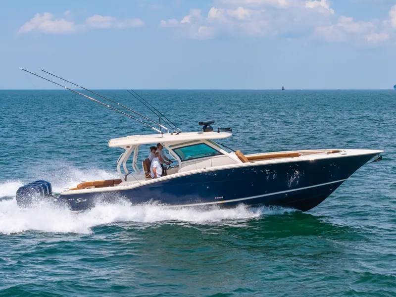 Slide: The Image of A 2016 Scout 42LXF boat speeds across the sea, with several people on board. - 6