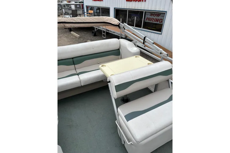 Slide: The Image of 2003 Smoker Craft Oasis boat interior with seating and table, parked near a building. - 13