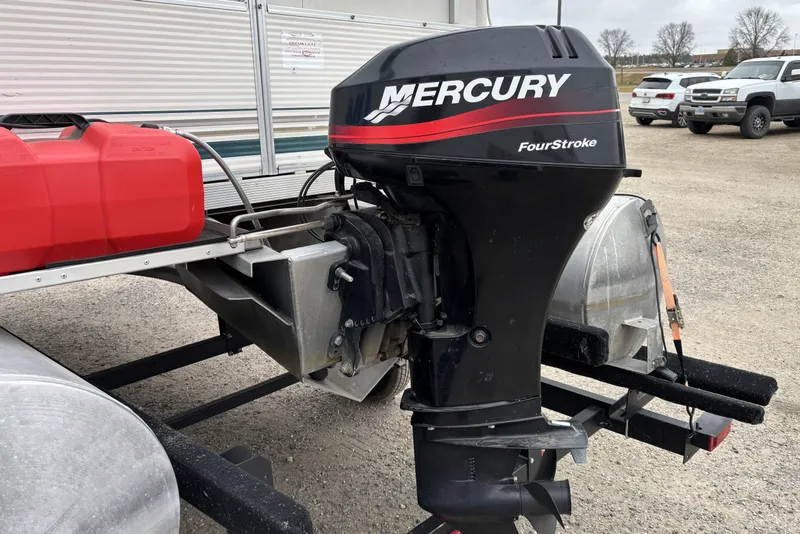 Slide: The Image of 2003 Smoker Craft Oasis with Mercury FourStroke outboard motor, parked on gravel. - 7
