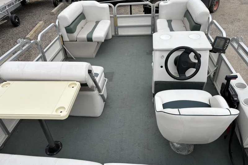 Slide: The Image of 2003 Smoker Craft Oasis pontoon boat interior with seating, table, and steering console. - 9
