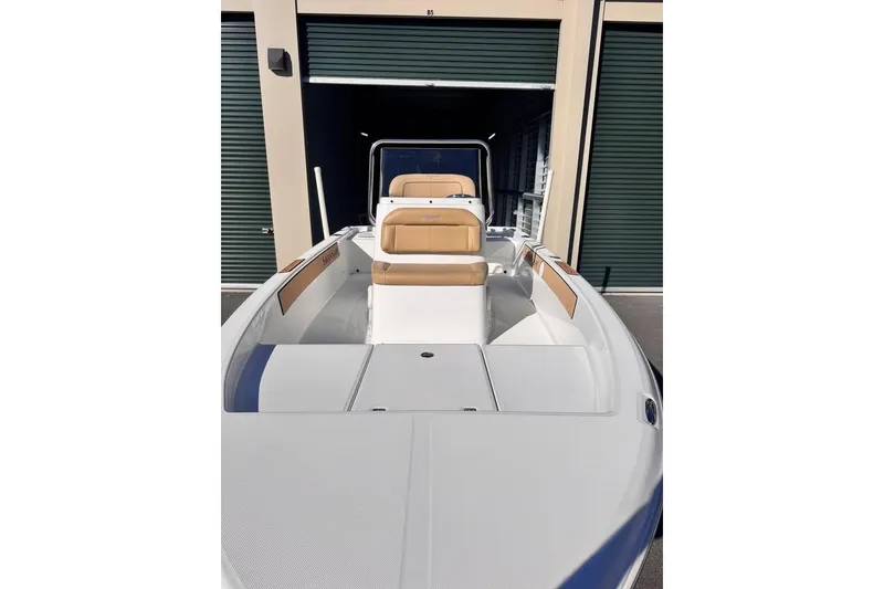 Slide: The Image of 2025 Savannah 190 IS boat with tan seating, docked near storage units. - 12