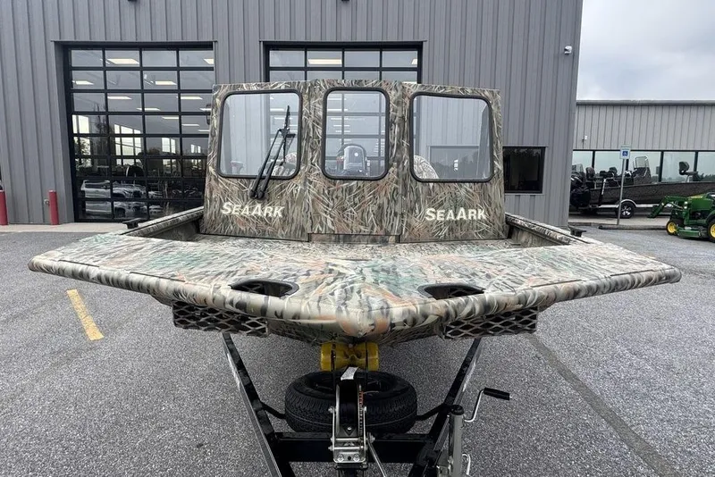 Slide: The Image of 2026 SeaArk 1872 MVJT boat with camouflage design on a trailer outside a building. - 10