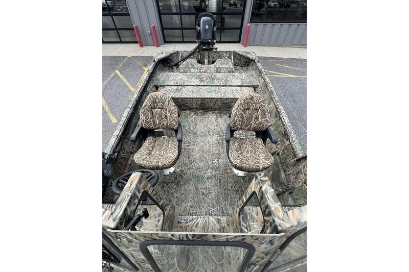 Slide: The Image of 2026 SeaArk 1872 MVJT boat with camouflage seats and flooring, parked outdoors. - 6