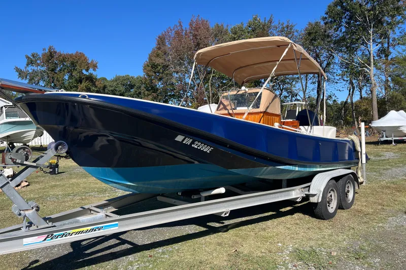The Image of 1971 Boston Whaler 21 Outrage boat on trailer, blue hull, parked outdoors. - 0