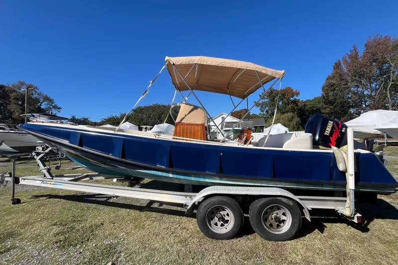 Slide: The Image of 1971 Boston Whaler 21 Outrage boat on trailer with canopy, parked outdoors. - 16
