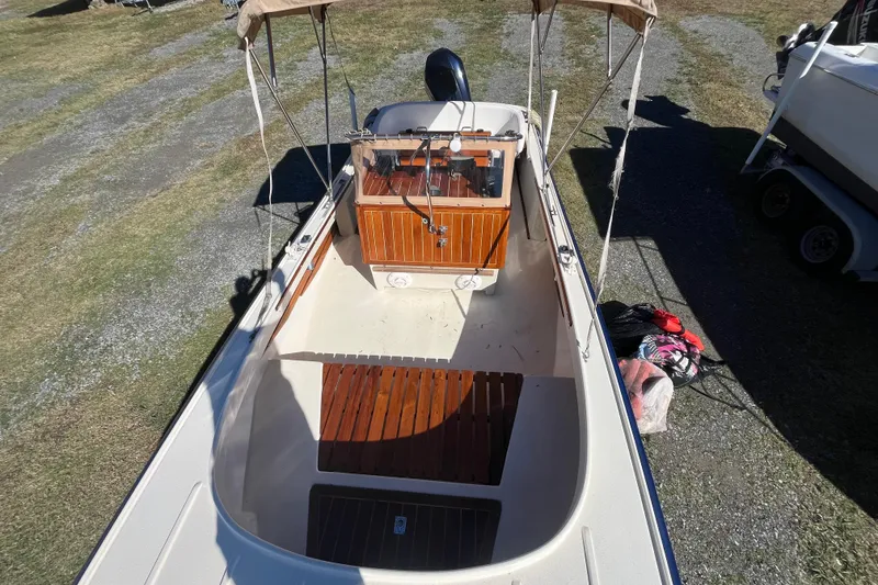 Slide: The Image of 1971 Boston Whaler 21 Outrage boat with wooden accents and canopy, parked on grass. - 2