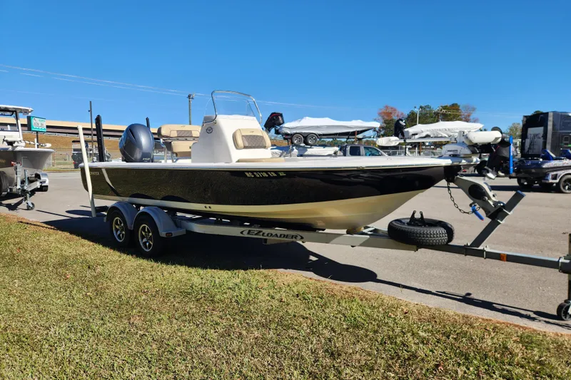 Slide: The Image of 2021 Tidewater 2110 Bay Max boat on trailer, parked outdoors under clear blue sky. - 6
