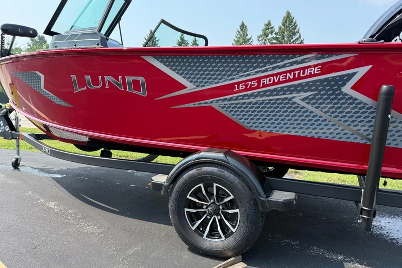 Slide: The Image of 2025 Lund 1675 Adventure Sport boat on trailer, red with gray graphics. - 2
