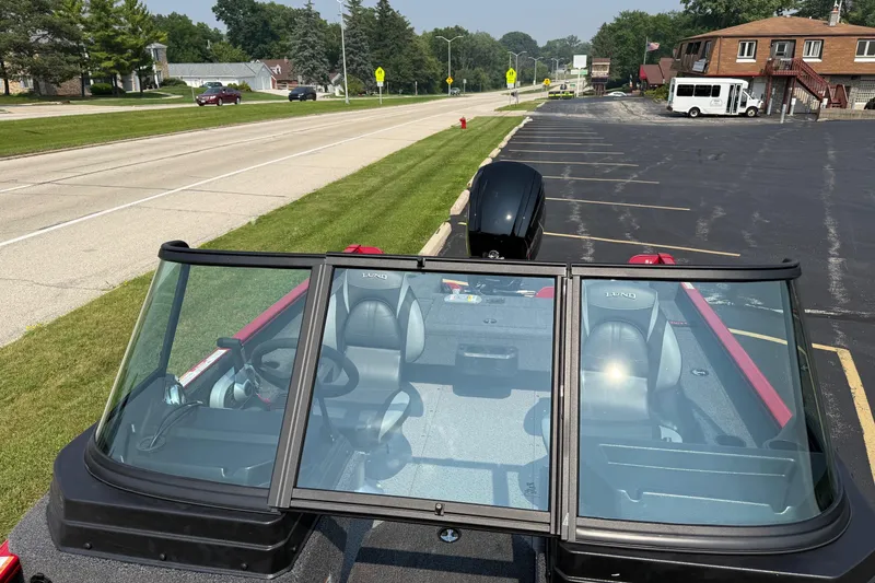 Slide: The Image of 2025 Lund 1675 Adventure Sport boat parked near a road, showcasing interior and windshield. - 22