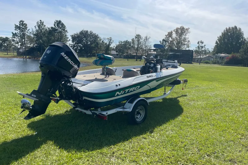 Slide: The Image of 2006 Nitro 640 LX boat with Mercury engine on grassy field near a pond. - 5