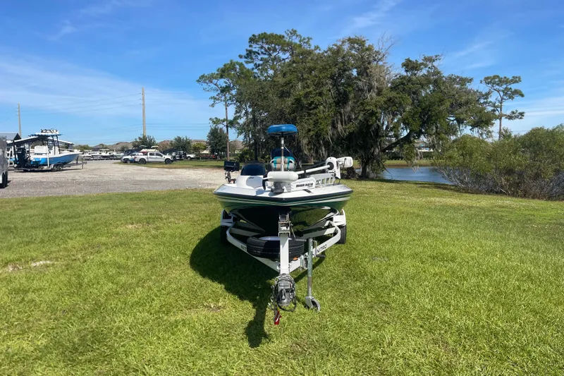 Slide: The Image of 2006 Nitro 640 LX boat on trailer, parked on grass near a lake under a clear blue sky. - 8