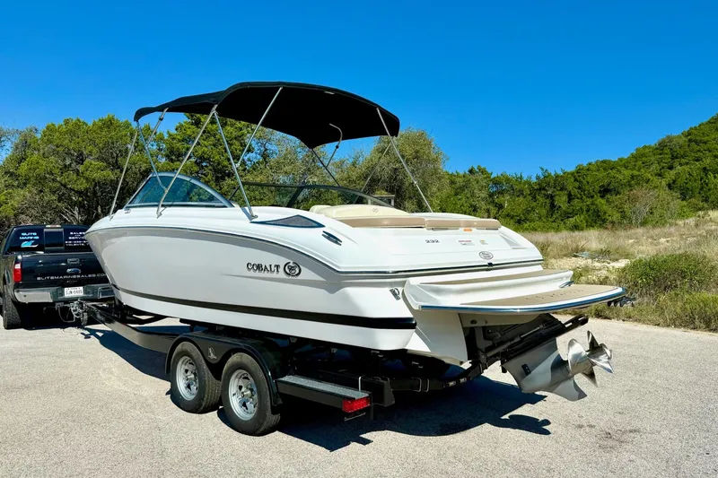 Slide: The Image of 2010 Cobalt 232 boat on trailer, parked outdoors under clear blue sky. - 11