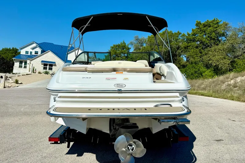 Slide: The Image of 2010 Cobalt 232 boat with canopy, parked on a sunny residential street. - 12