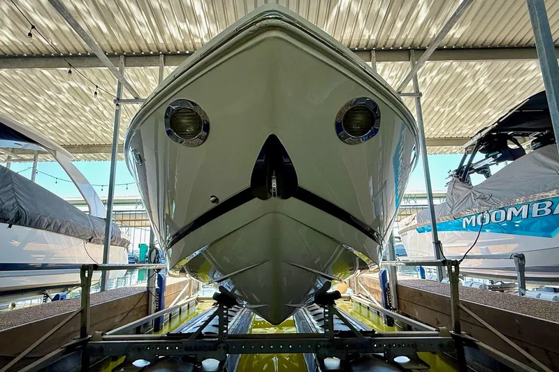 Slide: The Image of 2010 Cobalt 232 boat in storage, viewed from the front under a metal roof. - 17