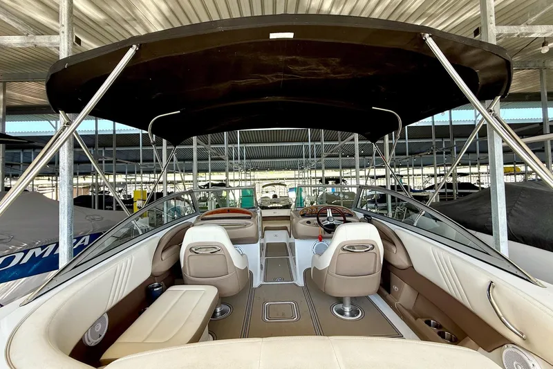 Slide: The Image of 2010 Cobalt 232 boat interior with seating and steering wheel under a canopy. - 22