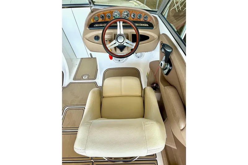 Slide: The Image of 2010 Cobalt 232 boat cockpit with beige seating and wooden steering wheel. - 26