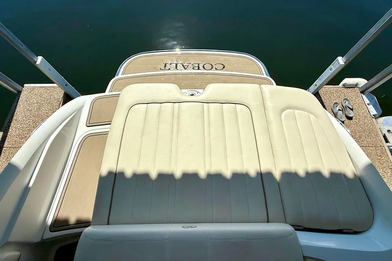 Slide: The Image of 2010 Cobalt 232 boat with beige seating and swim platform, docked by the water. - 31
