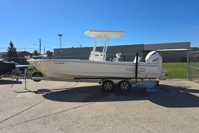 Slide: The Image of 2019 Robalo 246 Cayman boat on trailer, parked outdoors under clear blue sky. - 1