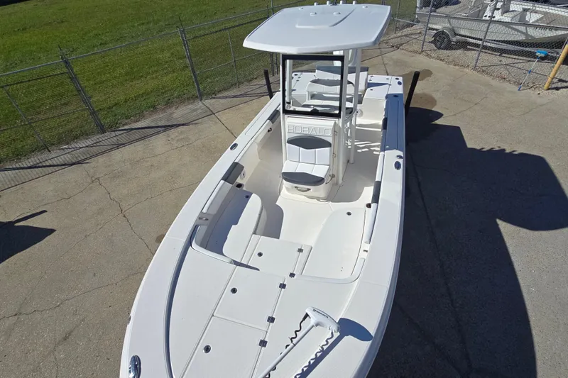 Slide: The Image of 2019 Robalo 246 Cayman boat, white exterior, parked on concrete near a fenced grassy area. - 14