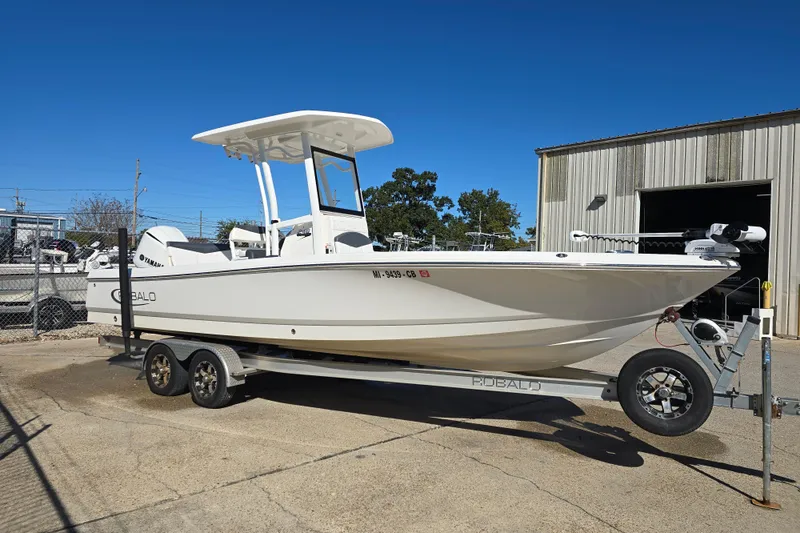 Slide: The Image of 2019 Robalo 246 Cayman boat on trailer, parked outdoors under clear blue sky. - 5