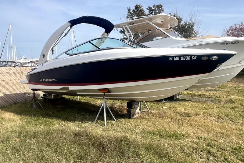Slide: The Image of 2016 Regal 2300 Bowrider boat on stands, parked on grass near marina. - 2