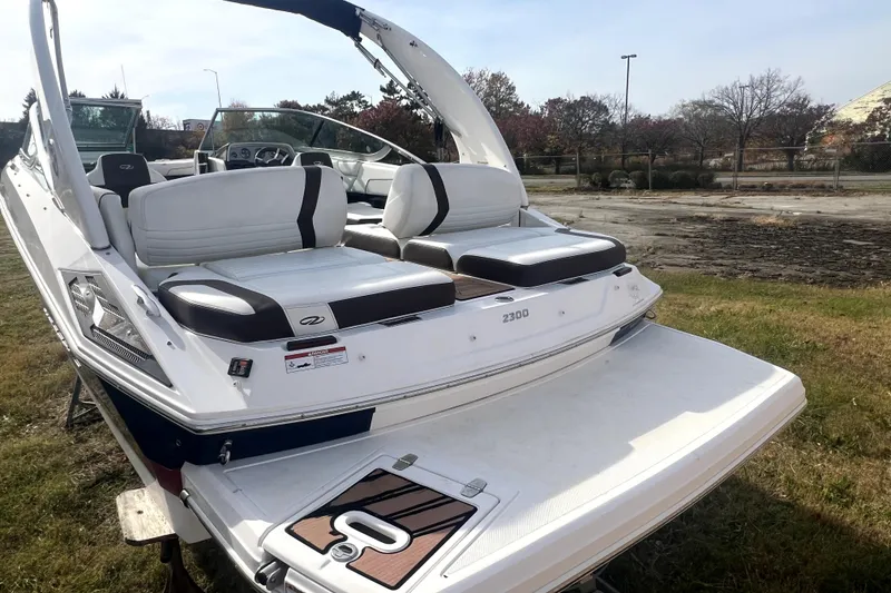 Slide: The Image of 2016 Regal 2300 Bowrider boat with white seating and swim platform, parked on grass. - 9