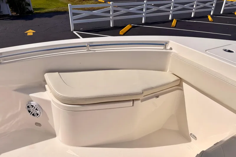 Slide: The Image of 2023 Cobia 220 Center Console boat with cushioned seating and speaker in a parking lot. - 10