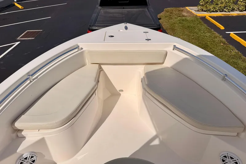 Slide: The Image of 2023 Cobia 220 Center Console boat with cushioned seating in a parking lot. - 7