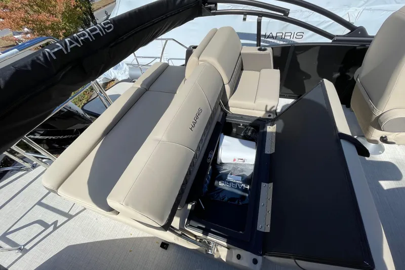 Slide: The Image of 2026 Harris Cruiser 250 boat interior with beige seating and storage compartment open. - 17
