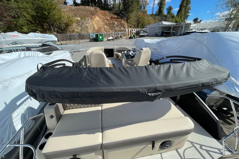 Slide: The Image of 2026 Harris Cruiser 250 pontoon boat with covered seating, parked outdoors. - 21