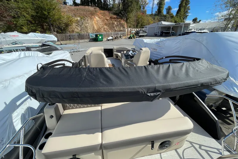 Slide: The Image of 2026 Harris Cruiser 250 pontoon boat with covered seating, parked outdoors. - 27
