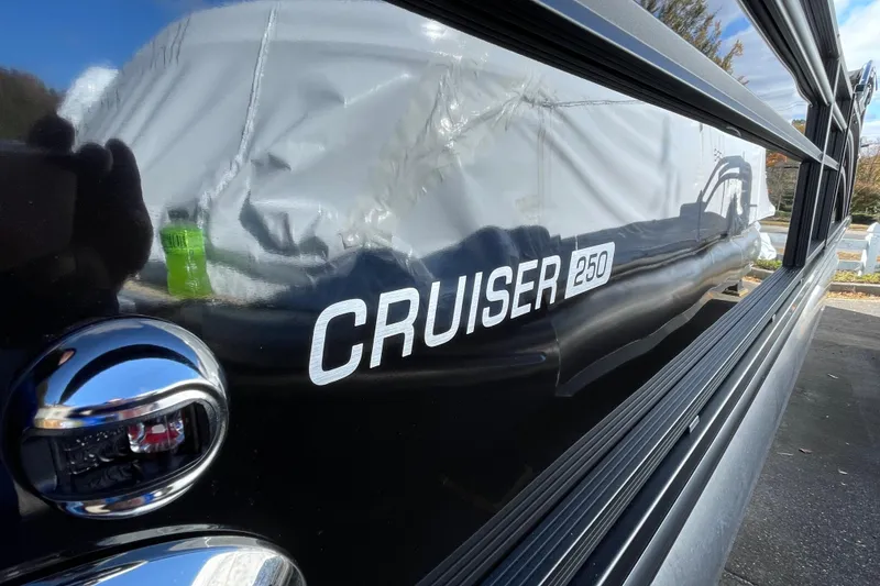 Slide: The Image of 2026 Harris Cruiser 250 boat with reflective black surface and chrome details. - 4