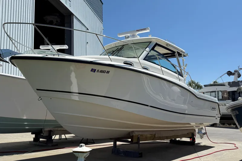 The Image of 2019 Boston Whaler 315 Conquest boat docked outdoors under clear blue sky. - 0