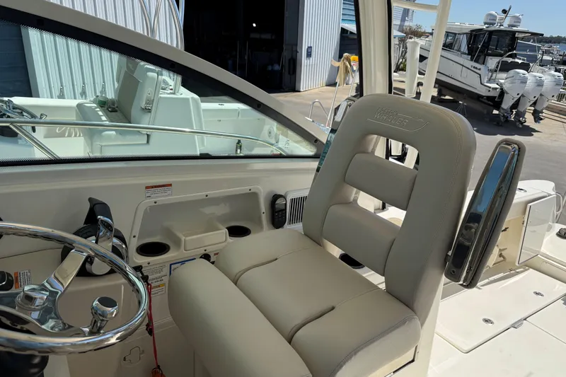 Slide: The Image of 2019 Boston Whaler 315 Conquest helm with steering wheel and cushioned seat. - 13