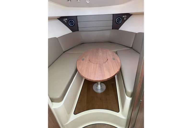 Slide: The Image of 2019 Boston Whaler 315 Conquest cabin interior with round wooden table and cushioned seating. - 16