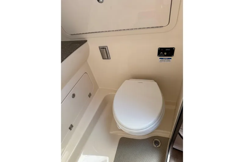 Slide: The Image of 2019 Boston Whaler 315 Conquest boat bathroom with toilet and storage compartments. - 18