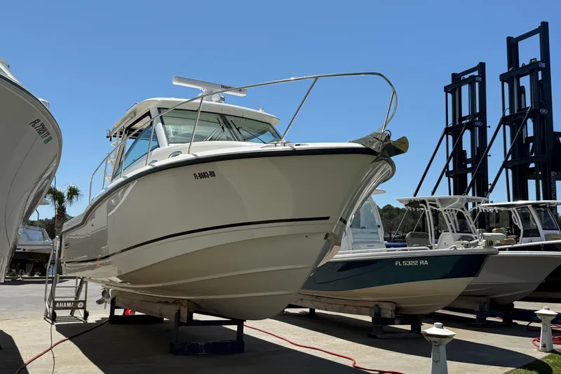 Slide: The Image of 2019 Boston Whaler 315 Conquest boat on display at a marina under clear blue skies. - 2