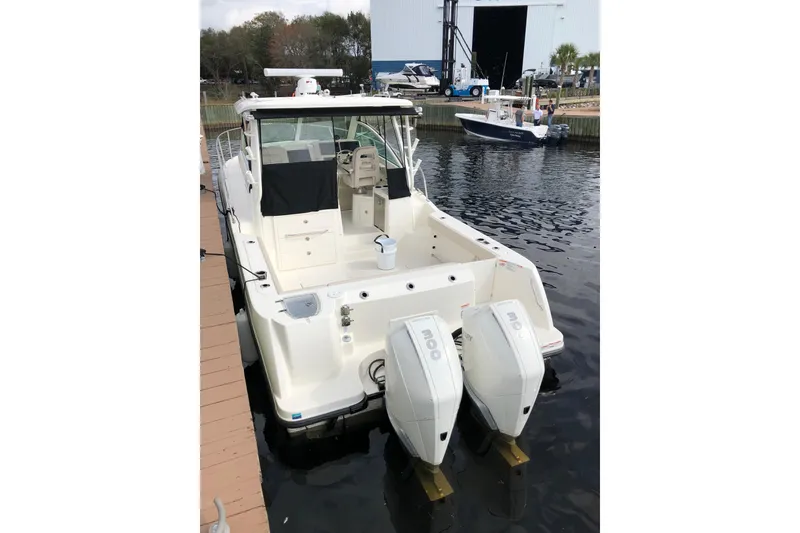 Slide: The Image of 2019 Boston Whaler 315 Conquest boat with dual outboard motors docked at marina. - 7