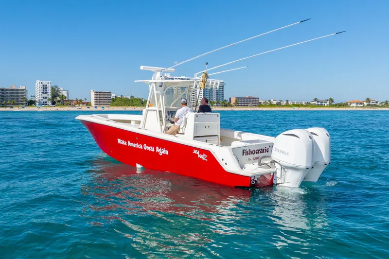 Slide: The Image of 2016 SeaVee 340Z boat with red hull, twin Yamaha engines, cruising near a coastal city. - 44