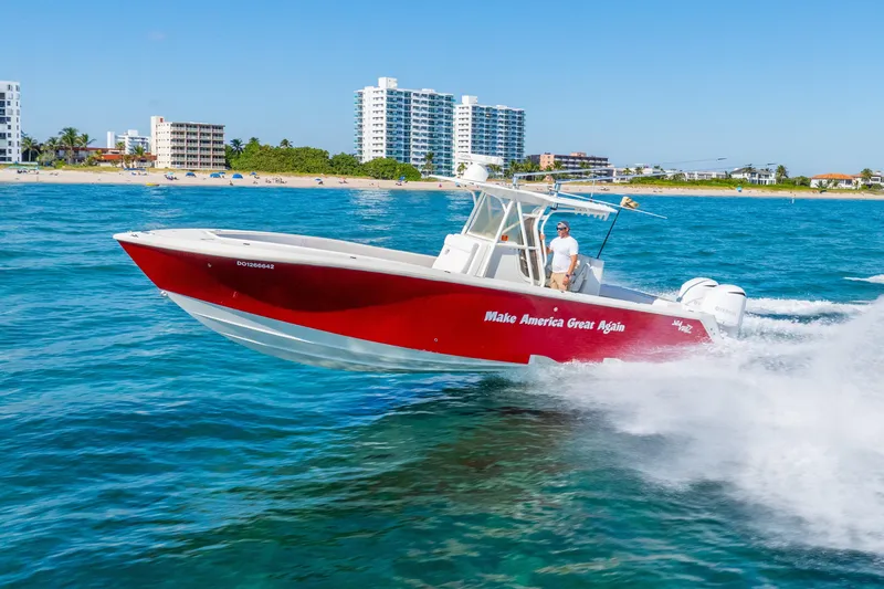 Slide: The Image of 2016 SeaVee 340Z boat cruising near a beach, vibrant red hull, clear blue water. - 59