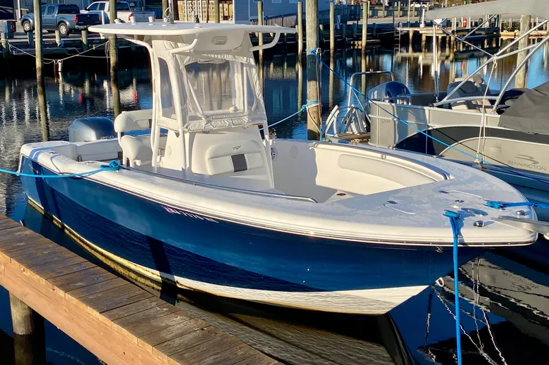 The Image of 2013 Tidewater 230 CC Adventure boat docked at marina, blue and white design. - 0