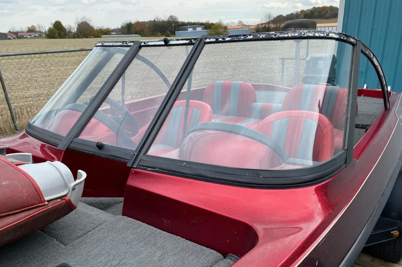 Slide: The Image of 1999 Ranger R77 Sport boat with red and gray interior, parked outdoors. - 13