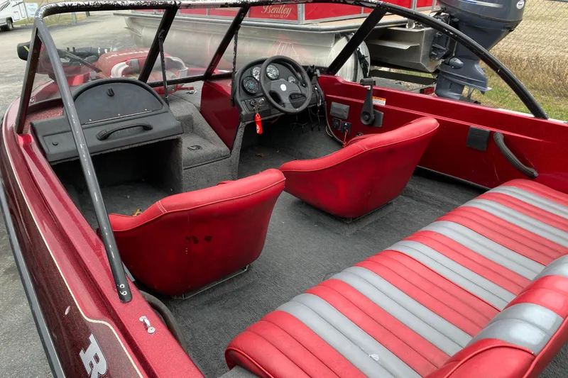 Slide: The Image of 1999 Ranger R77 Sport boat interior with red and gray seating, steering wheel, and dashboard. - 14
