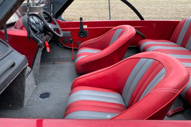 Slide: The Image of Interior of a 1999 Ranger R77 Sport boat with red and gray seating. - 16
