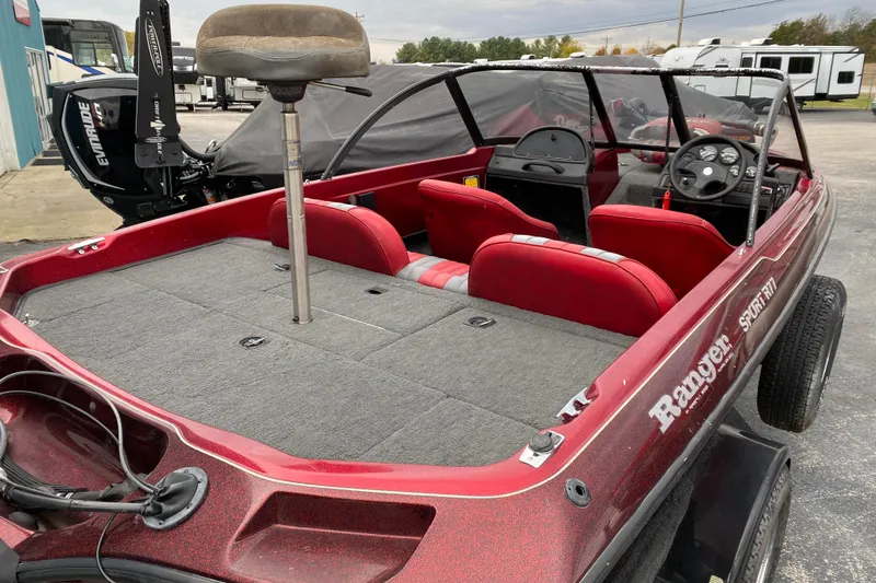 Slide: The Image of 1999 Ranger R77 Sport boat with red interior and Evinrude motor, parked outdoors. - 21