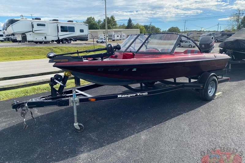 Slide: The Image of 1999 Ranger R77 Sport boat on trailer, parked near RVs, under a clear sky. - 3