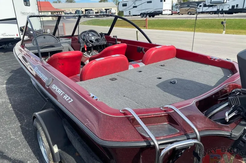 Slide: The Image of 1999 Ranger R77 Sport boat with red seats and spacious deck, parked near RVs. - 4