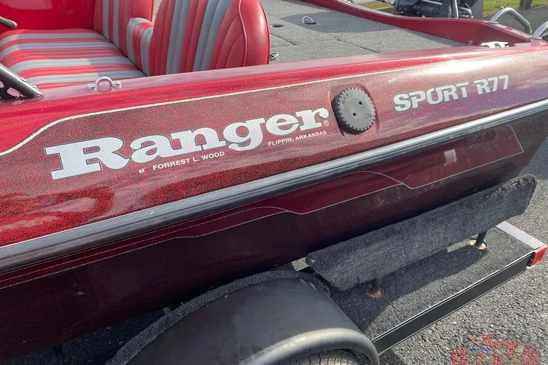 Slide: The Image of 1999 Ranger R77 Sport boat with red and gray interior, parked on a trailer. - 8