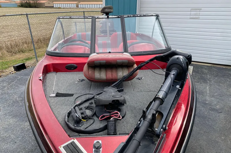 Slide: The Image of 1999 Ranger R77 Sport boat with red interior and trolling motor, parked outdoors. - 9